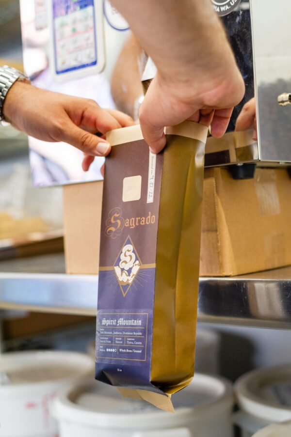 a staff filling in a bag with Sagrado Coffee beans